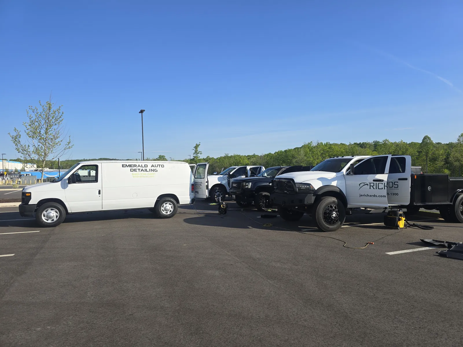 The Emerald Auto Detailing van set up alongside a row of work trucks in a commercial lot